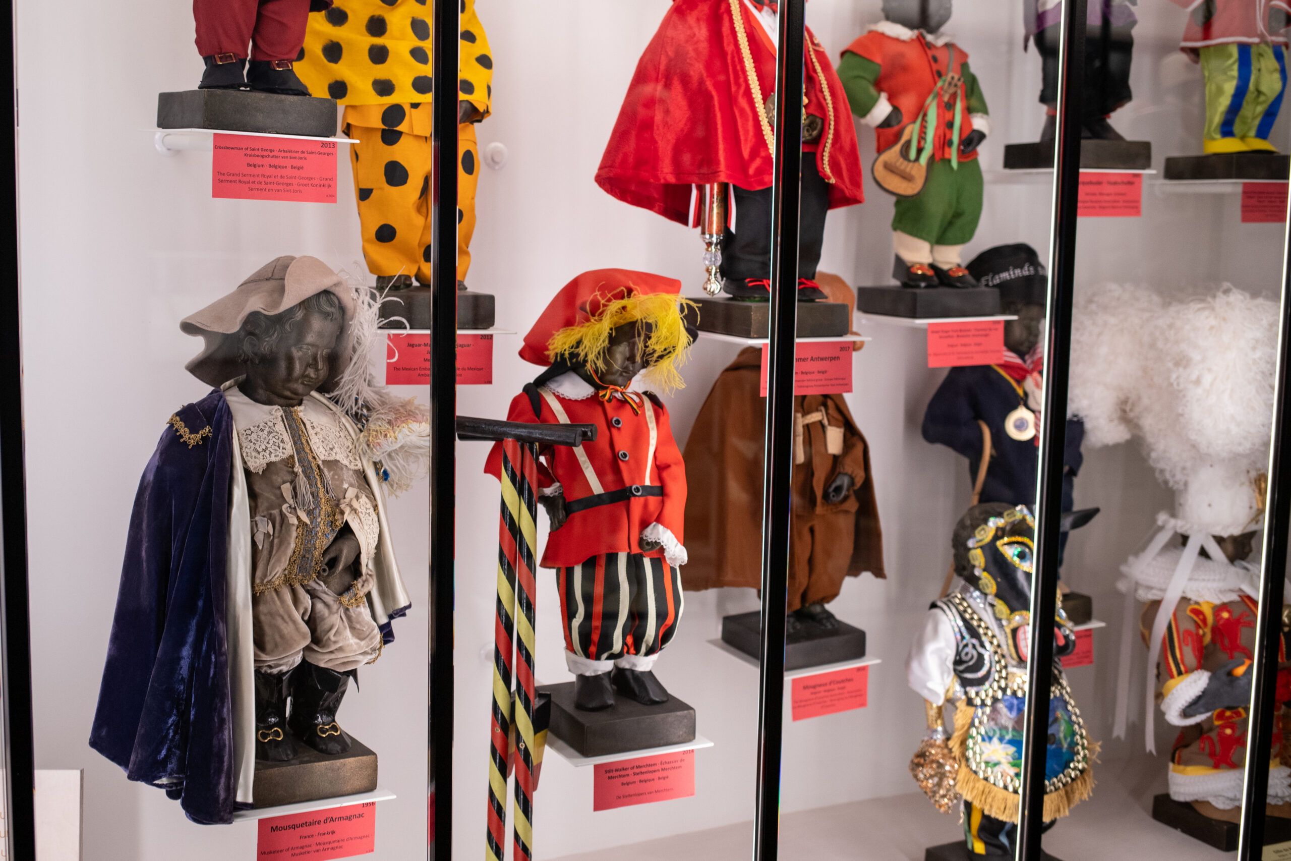 An exhibition display showcasing a colourful selection of Manneken-Pis costumes
